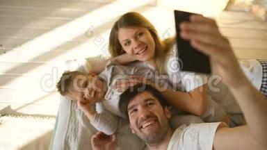 微笑的父母带着孩子在家里的床上自拍全家福